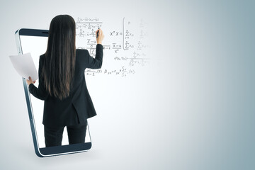 Attractive young european businesswoman inside abstract smartphone writing mathematical formulas on white background with mock up place. Online education and knowledge concept.
