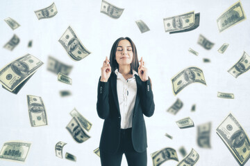 Attractive young european businesswoman with corssed fingers standing on white background with dollar banknote rain. Jackpot, wealth and lottery win concept.