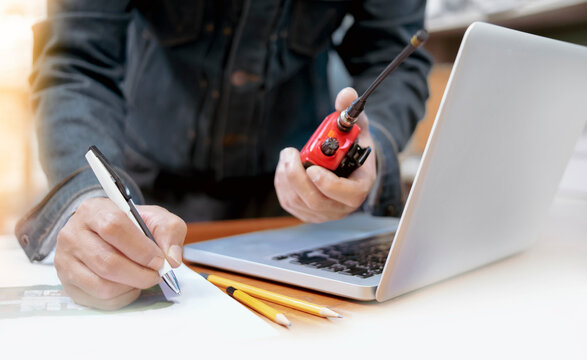 The team leader is speaking through a walkie-talkie at the construction site