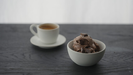 Chocolate ice cream in white bowl next to cup of espresso