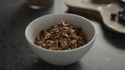 pour granola over yogurt in white bowl