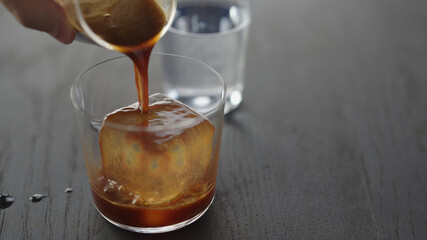 Making espresso tonic in tumbler glass, pour espresso over ice cube