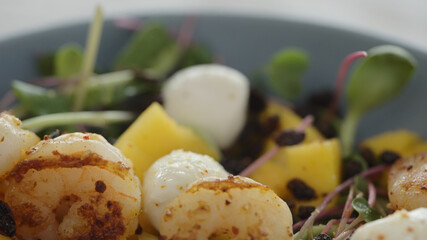 Salad with shrimps, mozzarella and mango on top of micro greens