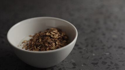 Pour granola over yogurt in white bowl