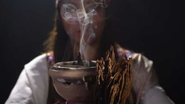 a spiritual woman holding burning tobacco and incense
