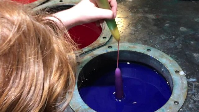 Children dipping and decorating candles in hot wax