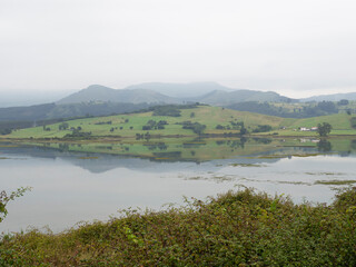 Fototapeta na wymiar Paisaje marítimo de brumas sobre las montañas reflejadas en el agua en el Camping El Rosal de Cantabria, España en verano de 2020. 