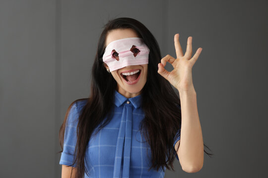 Young woman looking through holes on medical protective mask and showing hand ok gesture
