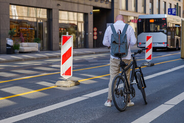 Adult man with backpack stand over bicycle on bicycle lane in downtown Düsseldorf, Germany.