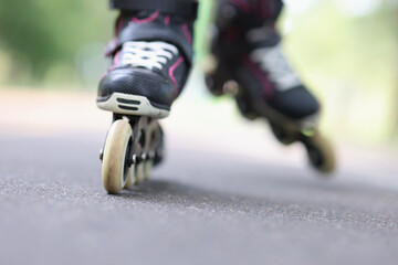 Child riding black rollerblades on road closeup