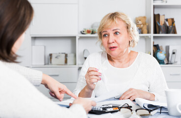 Accountant and a mature woman put in order financial home documents.