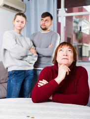 Chagrined senior woman having problems in relationship with young couple