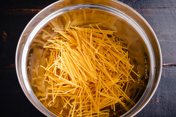 Broken Spaghetti Noodles in a Mixing Bowl: Overhead view of uncooked spaghetti noodles that have...