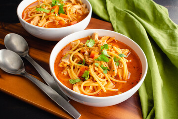 Cuban Style Chicken Noodle Soup Garnished with Cilantro: Bowls of chicken noodle soup in a tomato broth