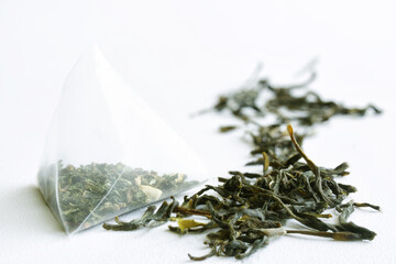 Tea bag pyramid with green tea on a white surface. Macro. Selective focusing. Daylight