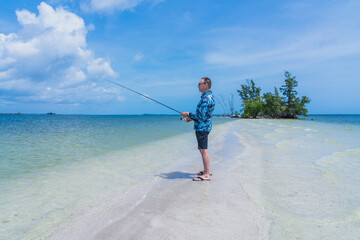 Caucasian man 60 years old with a fishing rod in his hands while fishing in the salt water of the...