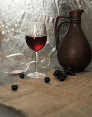 still life georgian jug and wine glasses on linen with a grape on stone background	