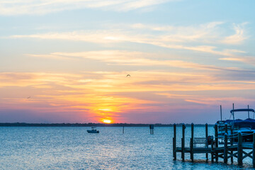 Obraz premium Orange sunset on Indian River, Vero Beach, Florida. Boats and wooden piers on the horizon