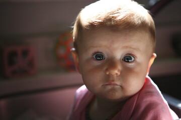 Portrait of a beautiful baby girl, content and peaceful, toys in background