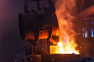 Molten metal is poured with sparks from ladle into mold. Smelting of multi-ton cast iron parts in...