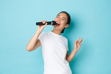Lifestyle, people and leisure concept. Passionate and carefree pretty asian girl singing song in...