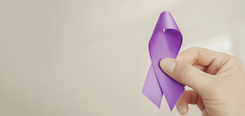 Hand holding purple ribbon, Alzheimer's disease, Pancreatic cancer, Epilepsy awareness, world cancer day