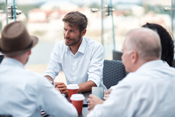 group of entrepreneurs discussing a joint project sitting at a discussion table.