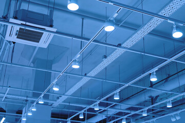 LED floodlights suspended from the ceiling on rails. lighting system in a shopping center, warehouse or office. Ceiling with bright lights in a modern commercial real estate object.