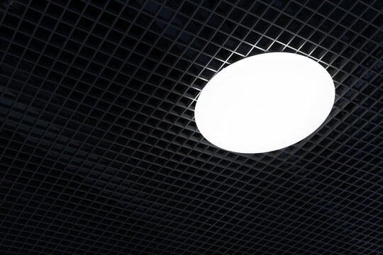 Modern Black Metal Grille Ceiling, Suspended Covering. Round Shape LED Lighting Lamp On Ceiling Of An Commercial Building. Grid Structure Of Suspended Ceiling In An Mall Building.