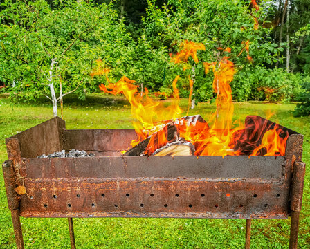 a photo of a barbecue in the backyard of a house with a large flame of fire rising from it