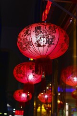 Traditional paper Red Chinese Lanterns glow in row on blurred night street. New Year celebration in Asia. Focus on foreground.