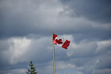 canadian flag waving against clouds
