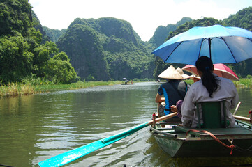 Fototapeta na wymiar Vietnamese people and foreign traveler travel visit and amazing boat tour trip Tam Coc Bich Dong or Halong Bay on Land and Ngo Dong river and cave of limestone mountains at Ninh Binh in Hanoi, Vietnam