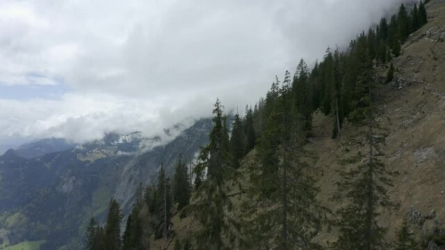 Aerial view moving forward shot, Scenic view of the side of a rocky mountain in Liezen Ennstal in Austria, sea of clouds surrounding the mountain in the background.
