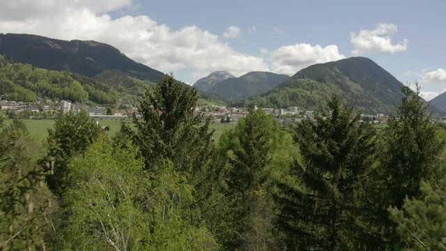 Aerial view moving forward shot, scenic view of the city of Liezen on a bright day in Austria, Green fields in the background.