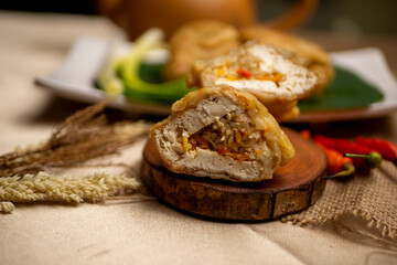Tahu isi, Indonesian traditional food, fried tofu filled with vegetables, served on wood plate on golden tablecloth