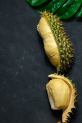 Durian fruit is ripe, specially selected size. Delicious and sweet yellow flesh, ready to eat, with peel, laid on a black wooden floor.