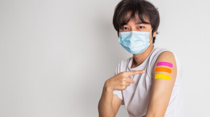 Asian man wearing face mask with a smile on his face showing his vaccinated arm. fight against virus covid-19 coronavirus, Vaccination and immunization. vaccine booster concept. - obrazy, fototapety, plakaty