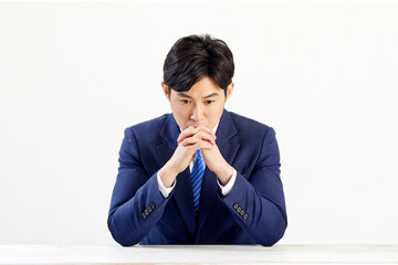 흰 배경 앞에 정장 입은 고민하는 30대 한국 남자