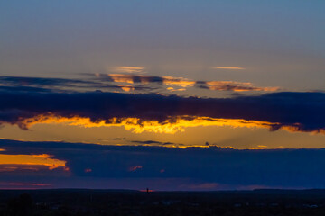the bright sun peeks out from behind the clouds at dawn on a warm summer morning