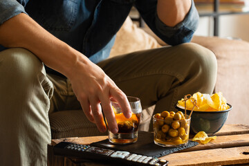 Man drinking vermouth and eating snacks after work at home