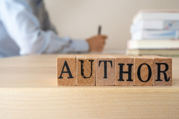 著者、筆者｜「AUTHOR」と書かれたスタンプと机に向かってペンを持つ男性