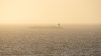 Lone Barge Moving Slowly Along Hazy Shoreline