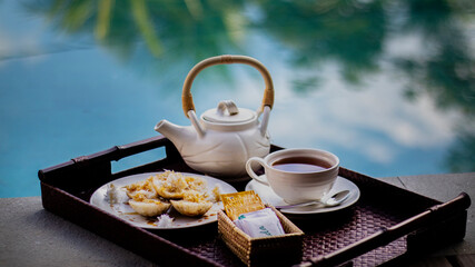 Afternoon tea with white Chinese style kettle and cup side of pool with natural light