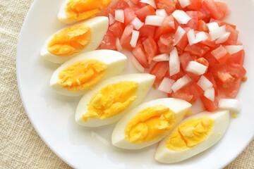 Boiled egg salad with tomatoes and onions on a white plate.  The concept of healthy and dietary food. Flat lay top view photo.  Food from above. 
