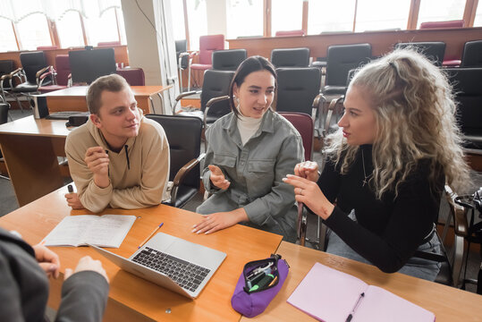 Two girls and a guy are talking in sign language. Three deaf students chatting in a university classroom.