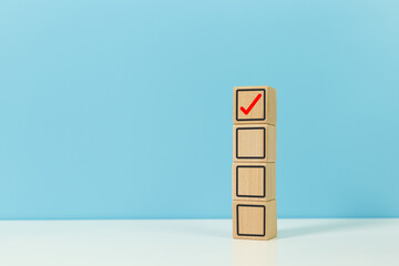 checklist and approval concept, wooden block with checklist icons blue background. answer decision yes vote.
