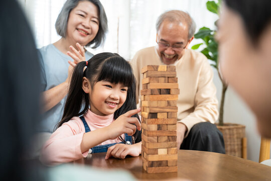 Asian happy family enjoy play toy block with little daughter in house.