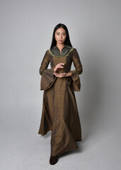 Naklejka premium Full length portrait of beautiful young asian woman with long hair wearing medieval fantasy gown costume. Graceful standing posing isolated on studio background.