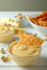 Snacks with cheese sauce on white wooden table